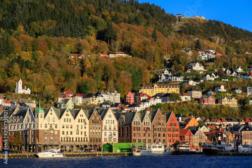 Panorama of Bergen Port with hanseatic buildings of World Heritage Site Bryggen, boats and mountain Fløyen with funicular railway Fløibanen in autumn in Norway