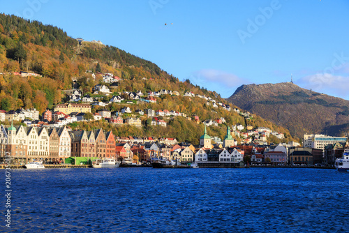 Panorama of Bergen Port with hanseatic buildings of World Heritage Site Bryggen, boats and mountain Fløyen with funicular railway Fløibanen and Ulriken in autumn in Norway