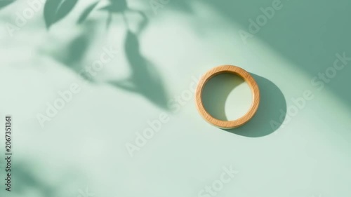 Wooden ring on pastel surface with leaf shadows decorative composition