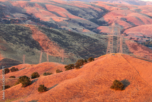 The rolling grass-covered hills of California's Coast Ranges bathed in warm golden-hour light, as seen from Santa Teresa County Park in San Jose.