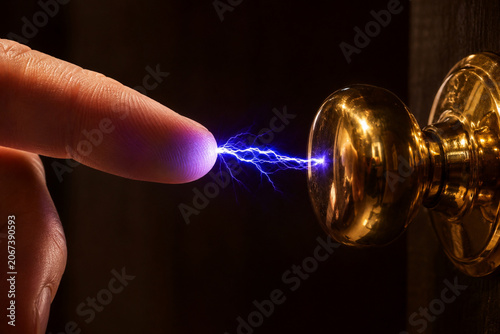 Macro Close Up of Blue Electric Static Discharge Spark Between Human Finger and Gold Door Knob on Dark Background