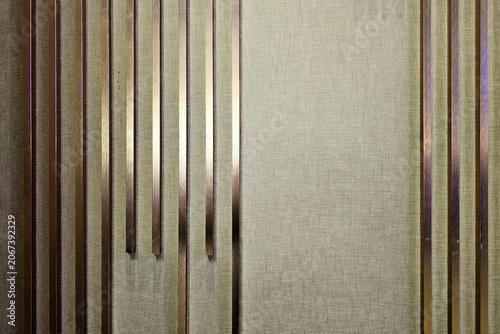 Принти на полотні Modern Decorative Wall Panel Featuring Vertical Bronze-Colored Metal Louvers Against Textured Light-Colored Fabric Background, Contemporary Interior Design Element