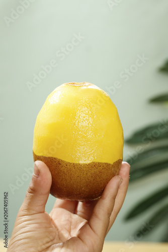 Billede på lærred Fresh Yellow Kiwi Fruit Half Peeled in Hand Still Life Photography