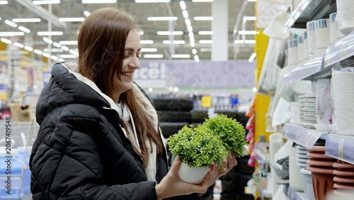 Bild auf Leinwand Happy shopper browsing small artificial potted plants in the gardening aisle of