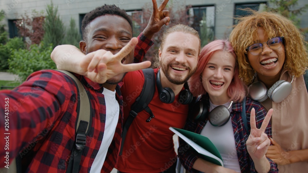 Fototapeta premium Web cam view four multiracial university students happy smiling cuddle posing looking at camera in city group of diversity friends diversity buddies smile cuddling together outdoors for selfie photo