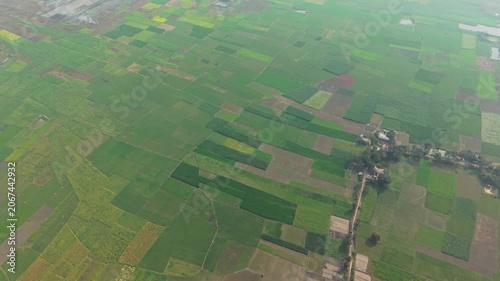 Aerial View of Green Patchwork Farmland Fields with Winding Roads and Farm Buildings in a Rural Landscape