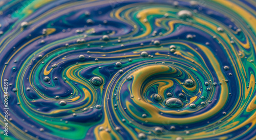Close-up shot of a colorful oil and water mixture with swirling patterns and bubbles on a flat surface with a mesmerizing mood.