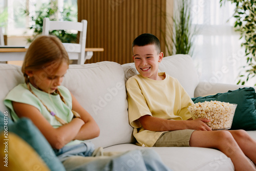 Sibling rivalry with boy teasing upset girl on sofa