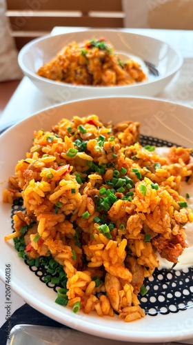 Spanish Style Fried Rice (Paella) with Chicken and Vegetables Served on White Plate