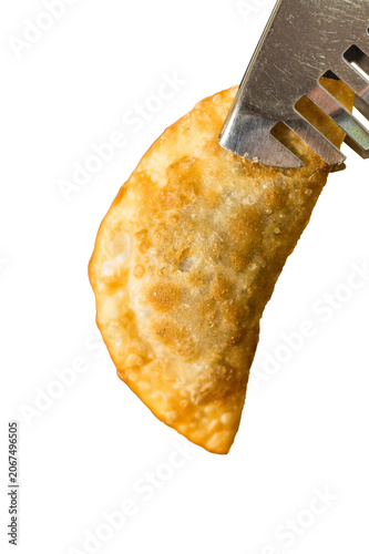 Crispy golden fried dumpling held by metal tongs, isolated