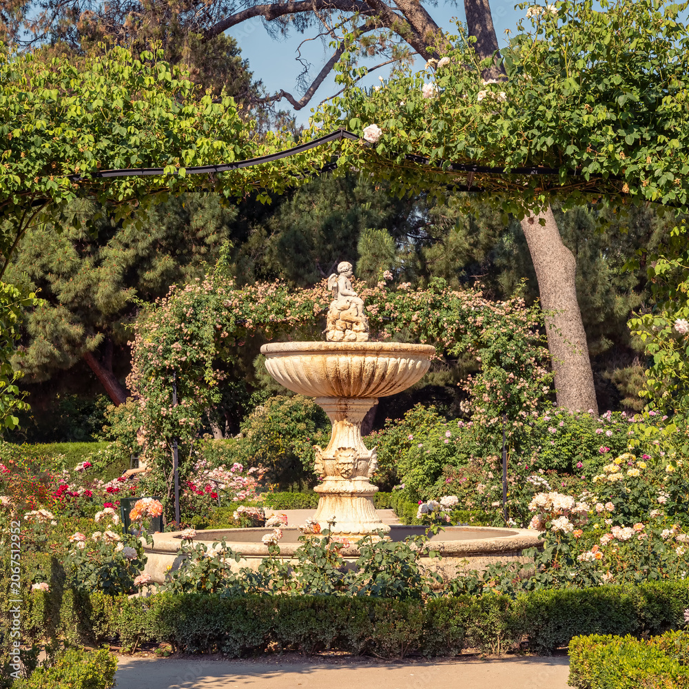 Obraz premium Beautiful garden with an ancient stone fountain in the huge Retiro Park in Madrid, Spain.