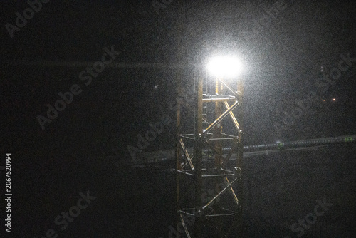 snow under the light of a construction crane at night