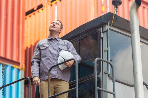 American engineer in uniform holding hard hat standing in containers yard, worker tired of frustration. 