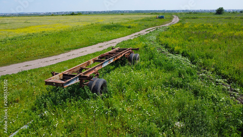 Bild auf Leinwand Aerial view of an abandoned rusty semi trailer chassis frame in a green summer f