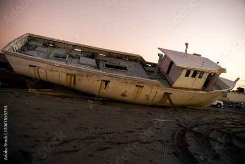 Fotografie Abandoned old shipwrecked boat on a sandy beach at sunset