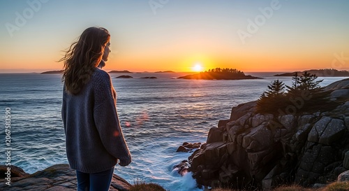 Woman in purple coat watching ocean sunset.