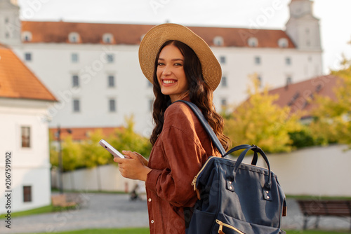 Принти на полотні Happy woman tourist with cellphone in hands near historic site in the city