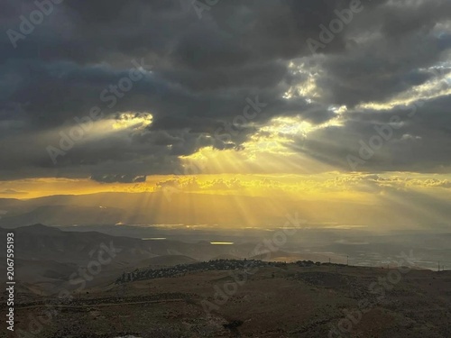 Photography Dramatic mountain landscape at golden hour with dark heavy clouds, radiant crepu