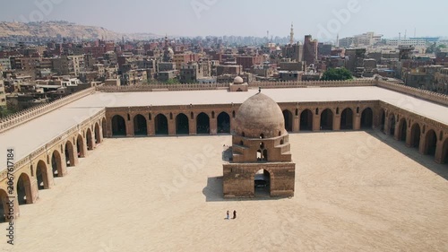 Courtyard of Ibn Tulun Mosque, oldest mosque located in Islamic Cairo, Egypt. Vast historic mosque courtyard surrounded by arcaded colonnades and dominated by a central domed ablution fountain.
