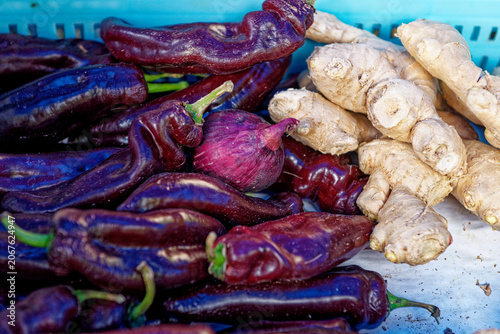 Purple chili peppers, a single red onion, and fresh ginger roots
