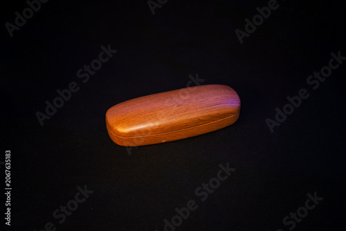 Tableau sur toile A sleek, closed hard-shell glasses protector case in vibrant orange color, resting on a dark low-key surface