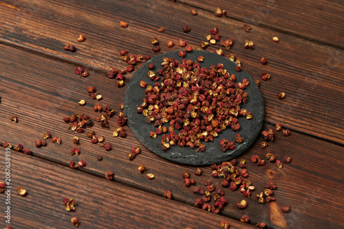 фотографія Dried Sichuan Peppercorns on Slate Plate and Rustic Wooden Table