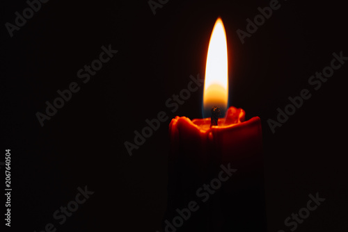 Lit red wax candle with expressive melted texture on a black background. Dramatic close-up glow, contrast, and material transformation, suitable for emotional, symbolic, and contemporary concepts.