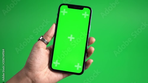 Hands holding smartphone with green screen on green background
