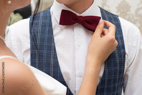 groom in a wedding suit with a bow tie. The bride's hands