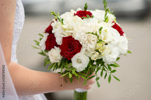 A bride holding a bouquet of pink and white roses in her hands.