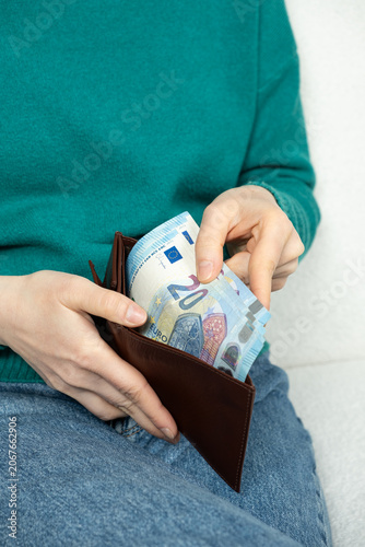 Hands holding a leather purse with visible paper money.
