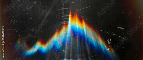 Prismatic light refraction effect on dark surface with scratch texture for digital design.