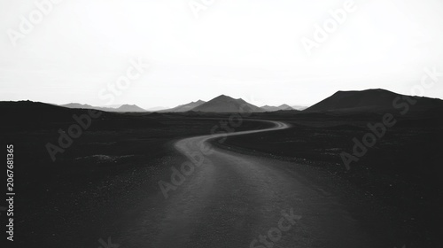 Low Angle Winding Gravel Road S Curve Desolate Volcanic Landscape Layered Mountain Silhouette Minimalist Monochrome Black White Overcast Sky Negative Space Film Grain Web Background Design Material
