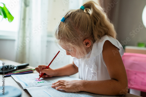 Fényképezés Girl concentrating on writing exercise at home, close-up