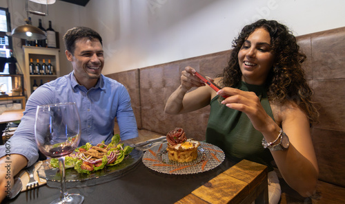 Canvastavla A woman takes photos of her plate of food whilst having dinner with her husband