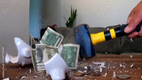 Hand smashing a white piggy bank with a hammer in slow motion