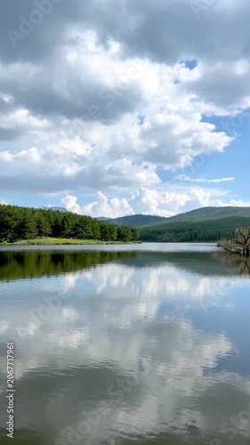 Peaceful mountain lake reflecting a beautiful cloudy sky. The serene water ripples gently, creating a tranquil and scenic nature view