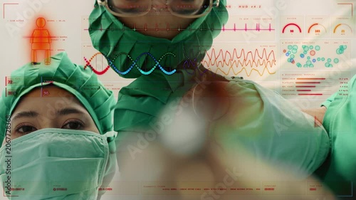 Group of Asian surgeons in scrubs looking down at a patient with a futuristic medical HUD interface overlay showing surgery metrics and life support data, representing high tech healthcare
