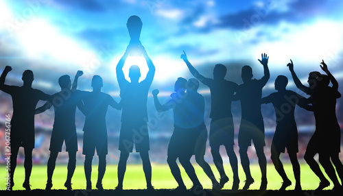 Silhouette of a winning soccer team celebrating victory and lifting up a championship trophy cup.