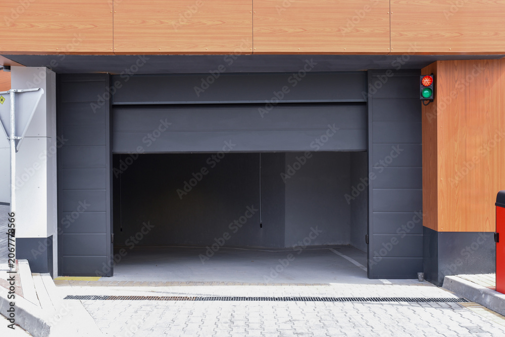 Fototapeta premium Partially open automatic sectional garage door on modern building facade