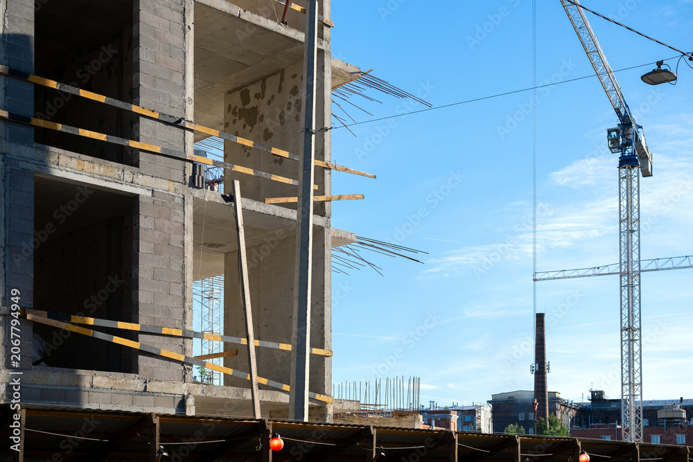 Naklejka premium Building Under Construction with Tower Crane Against Blue Sky