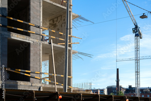 Building Under Construction with Tower Crane Against Blue Sky