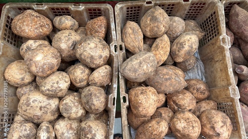 High angle view of fresh raw sweet potatoes and taro roots in plastic crates at a traditional market