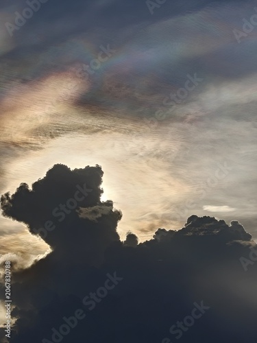 Iridescent Cloud Streaks Above Dark Cloud Silhouette at Dusk