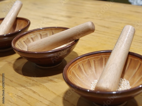 Wooden Mortar and Pestle Bowls with Sesame Seeds on Table