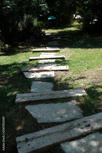 Rustic Stone and Wooden Plank Garden Path Leading Through a Lush Green Landscape