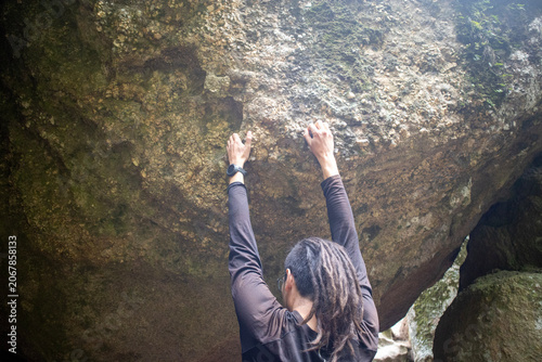 Quadro su tela Man with dreadlocks bouldering on a massive rock overhang