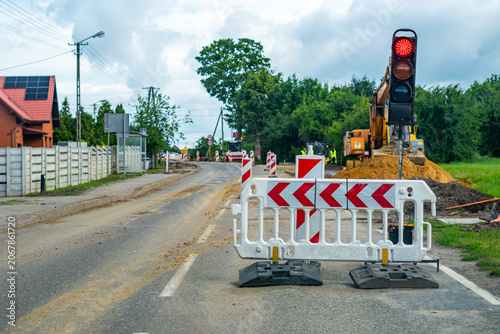 фотографія Roadworks on a suburban street, portable traffic light showing red signal, plast