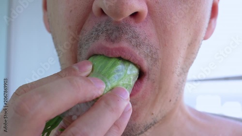 Close up view of a man's mouth eating a fresh vietnamese spring roll, demonstrating a healthy and delicious meal. The man bites into the rice paper wrap filled with lettuce and other tasty fillings