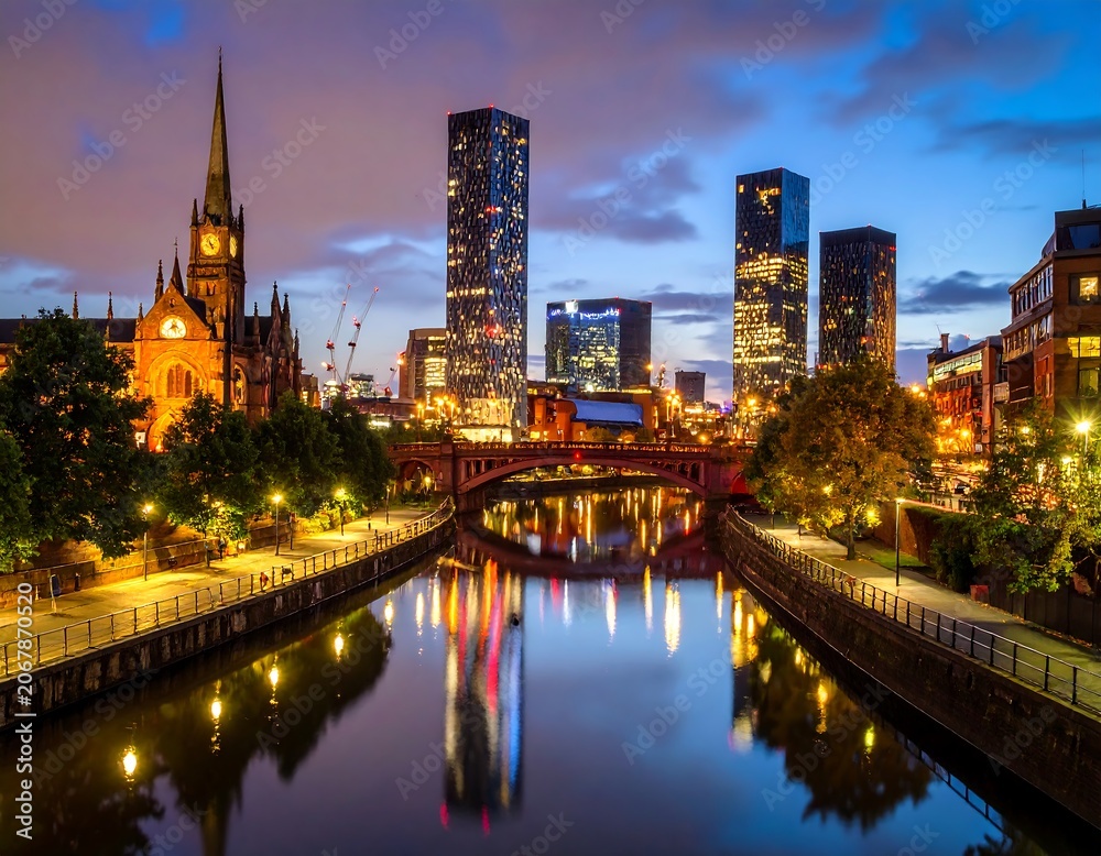 Obraz premium A scenic cityscape at dusk, featuring a river reflecting lit buildings and a historic church with a prominent spire